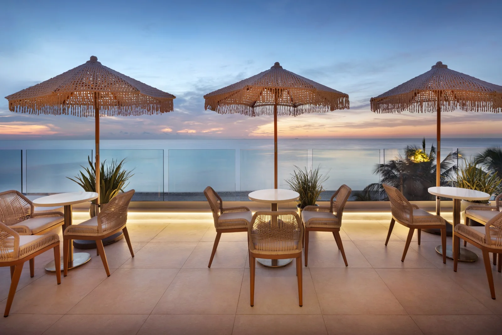 Oceanfront terrace with woven umbrellas and ocean views at Kalypso Beach in Miami Beach